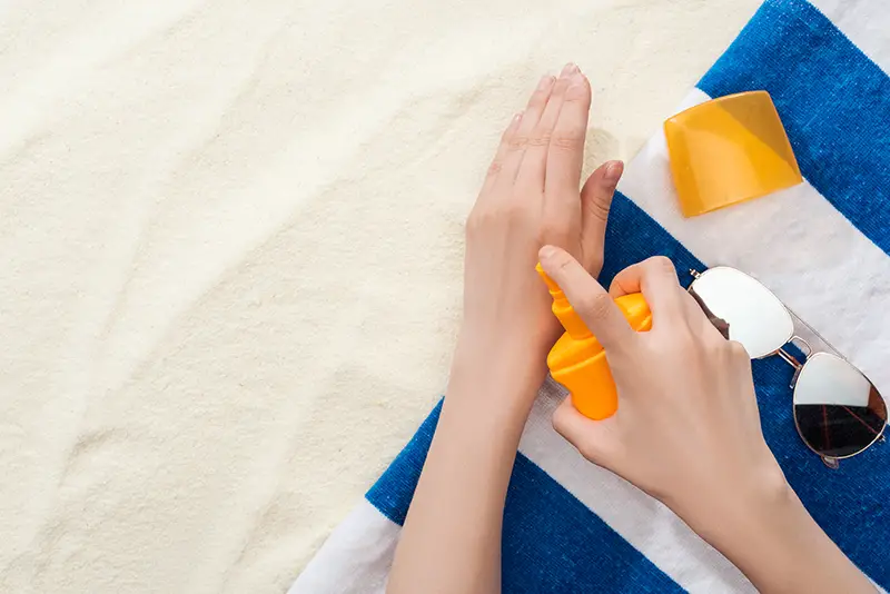 Cropped view of woman applying sunscreen on her hands