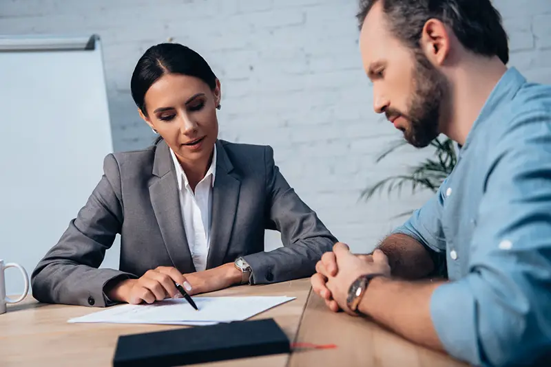 Female lawyer holding pen and insurance documents talking to male a client