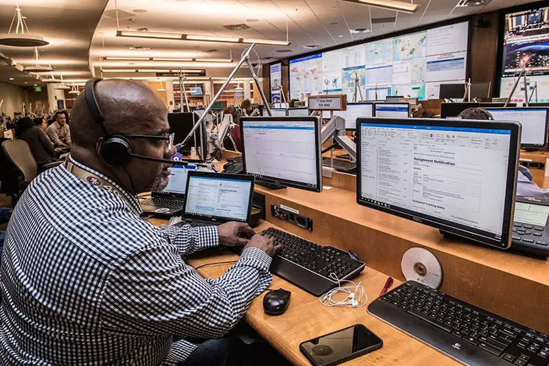 Male African wearing headset while working in front of computer screen