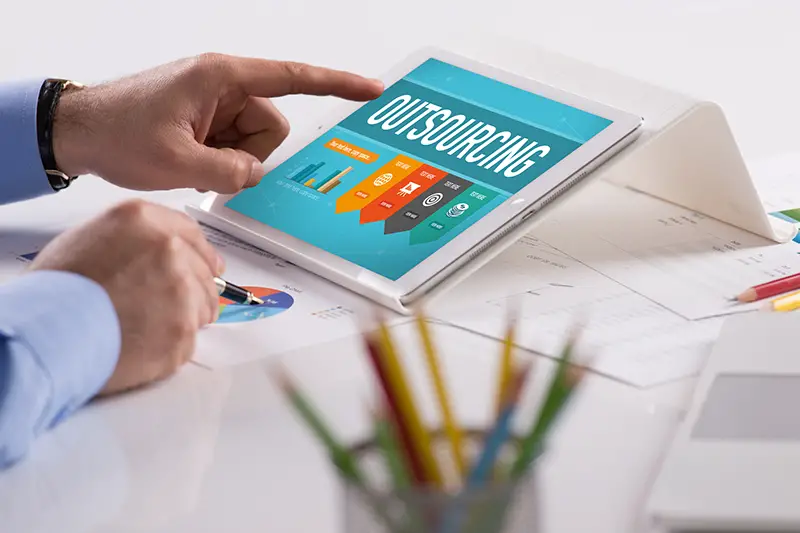 Businessman working on tablet with OUTSOURCING on a screen