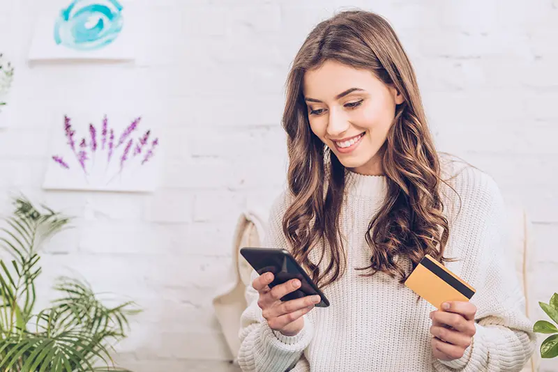 Beautiful young woman smiling while holding credit card