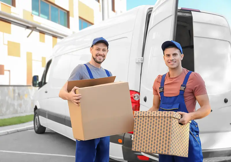 Delivery men with moving boxes near car