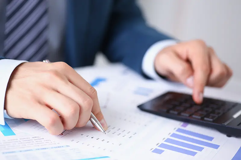 Black calculator and financial statistics on infographics at office table closeup.