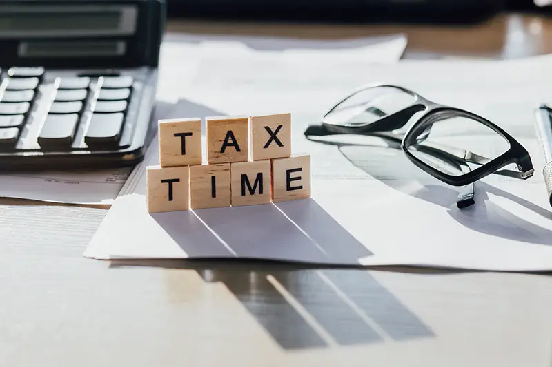 Tax Time wooden letters with tax form, glasses and calculator