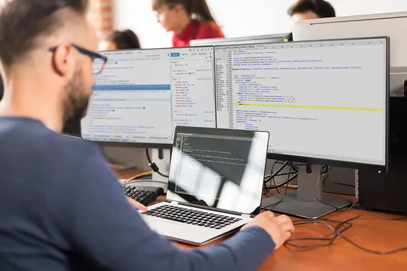 Man working in front of his computer and laptop screen