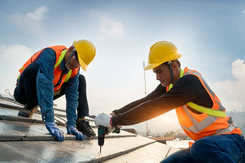 Construction worker wearing safety harness belt during working on roof structure of building on construction site