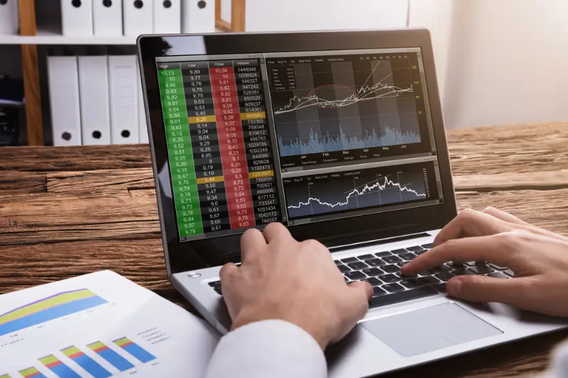 Close-up Of A Stock Market Broker's Hand looking at the graphs