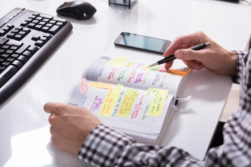 Businessperson writing schedule on diary