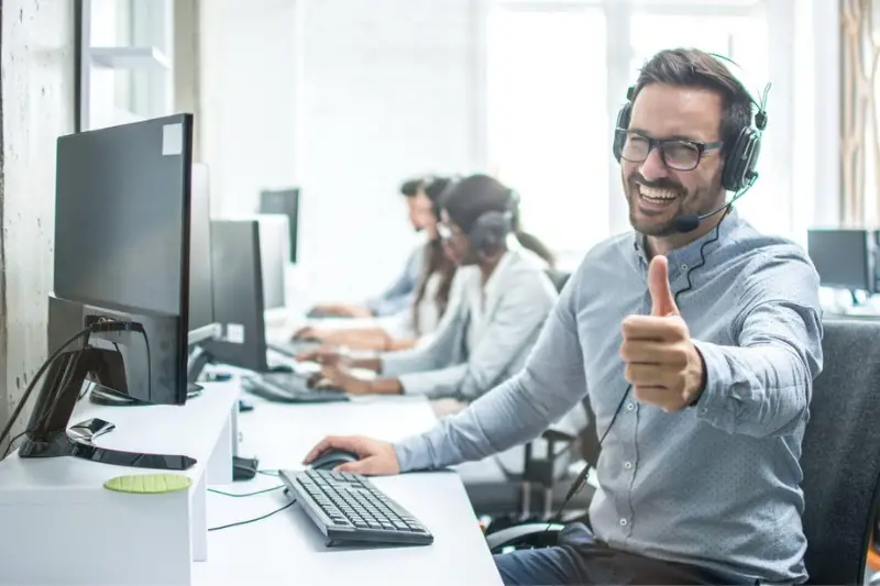 Smiling man wearing headset working in call center