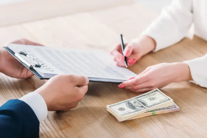 Partial view of woman signing contract on clipboards