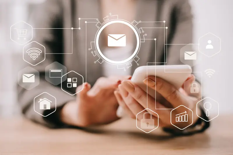 Cropped view of businesswoman using smartphone in office with email icons