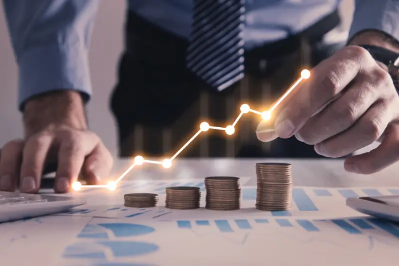 Man stacking coins with a graph of profit