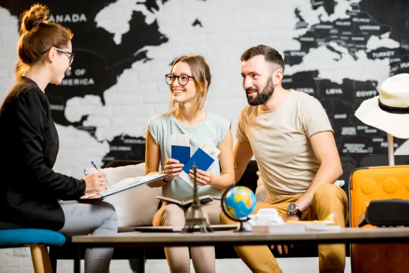 Young lovely couple sitting with manager at the travel agency office prepairing for a summer vacation