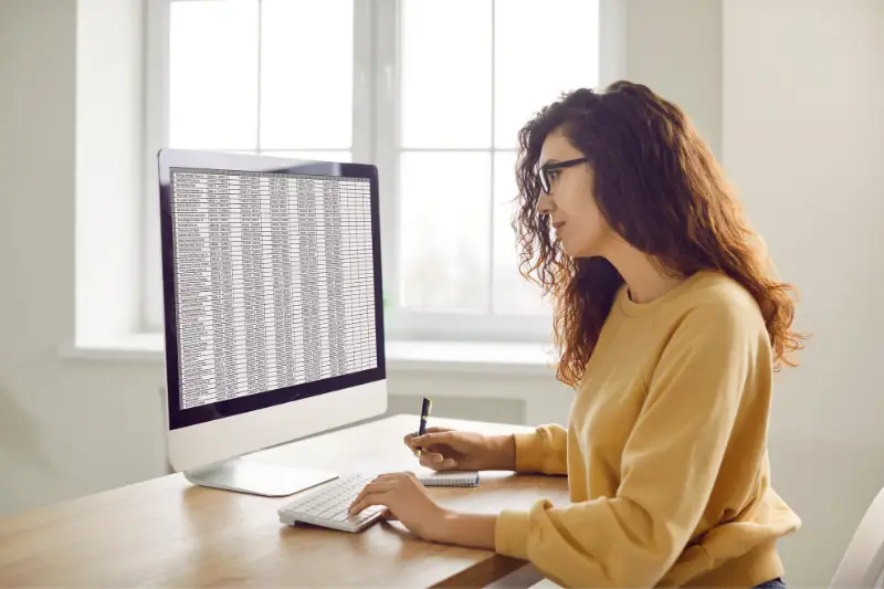 Female accountant working with digital business spreadsheets on office computer.