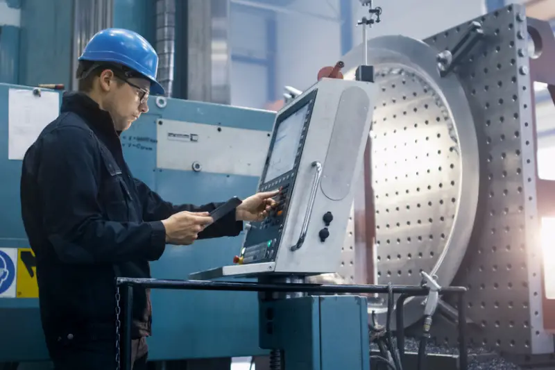 Factory worker is programming a CNC milling machine