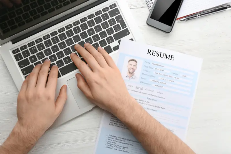 Man with resume form using laptop at table