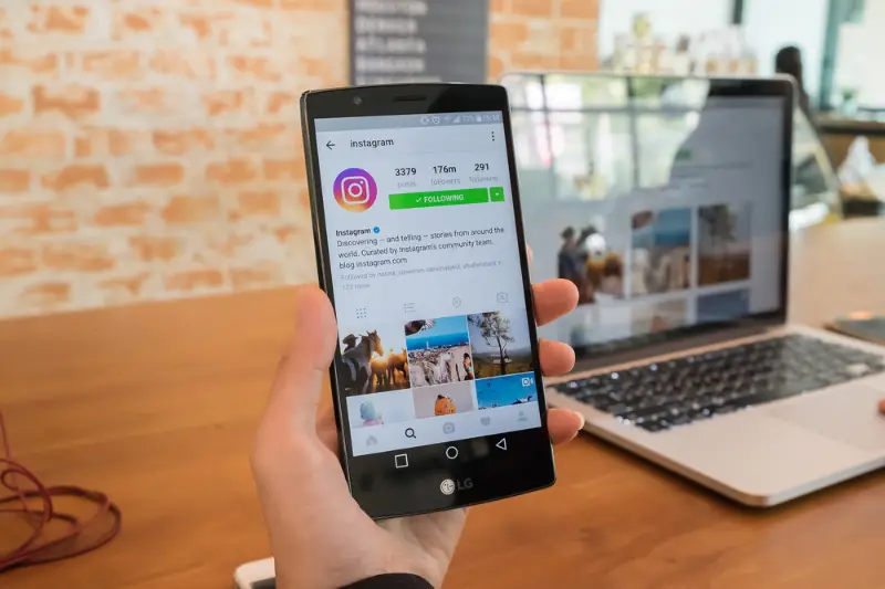 Woman hand holding smartphone with instagram account on the screen