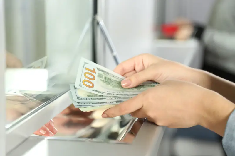 Female hand with money in cash department window