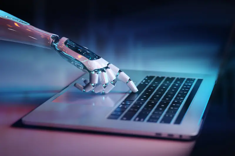 Robotic hand pressing a keyboard on a laptop