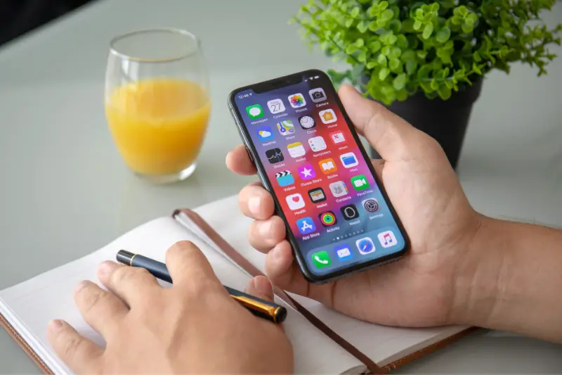 Man hand holding iPhone X with home screen IOS