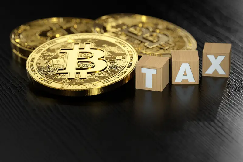 Stack of Bitcoin laying next to wooden blocks with TAX letters