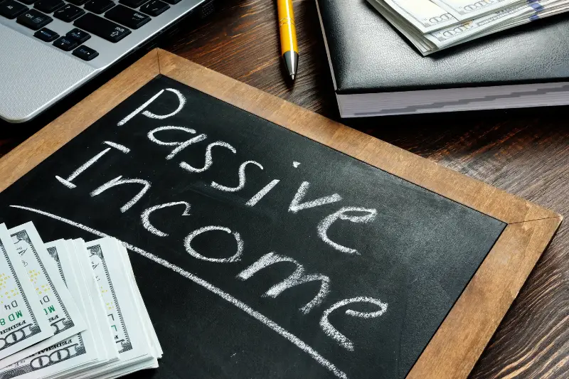 Passive income inscription on the board and a bundle of bills.