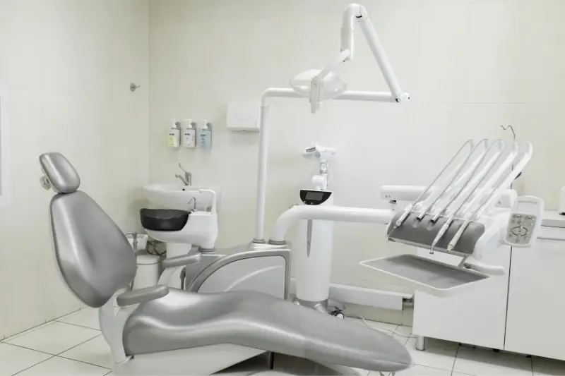 A modern, well-equipped dentist's office, a patient's gray chair. Machine for drilling teeth and other dental equipment