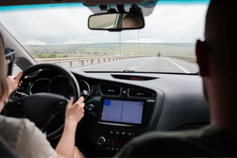 A woman drives her car. Route navigator map, back view