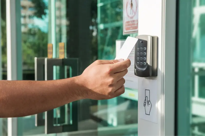 Hand using security key card scanning to open the door to entering private building.