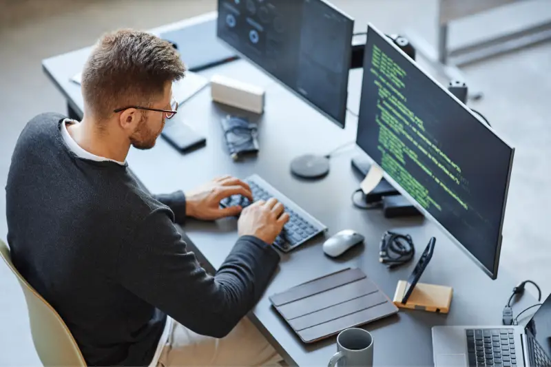 High angle view at software developer writing code while using computer and data systems in office