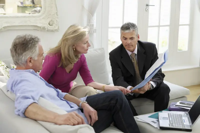 Mature couple sitting on sofa with financial advisor