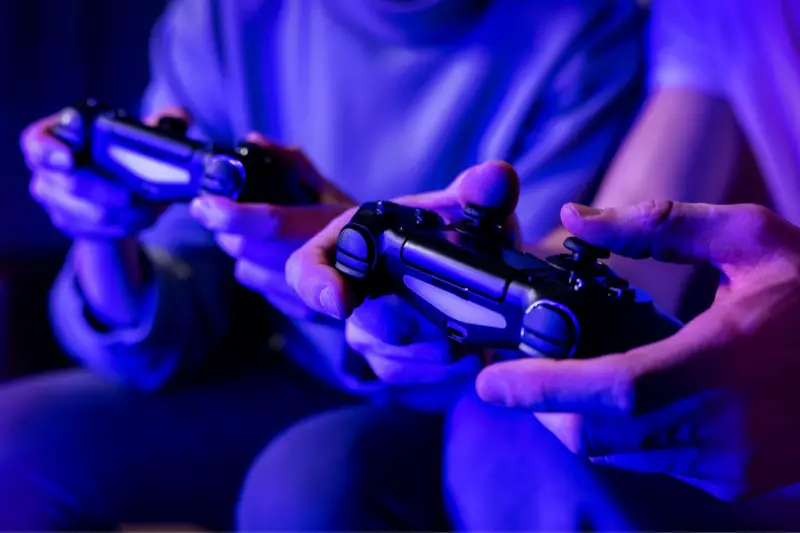 friends playing console video games. controller in hands closeup. neon lights