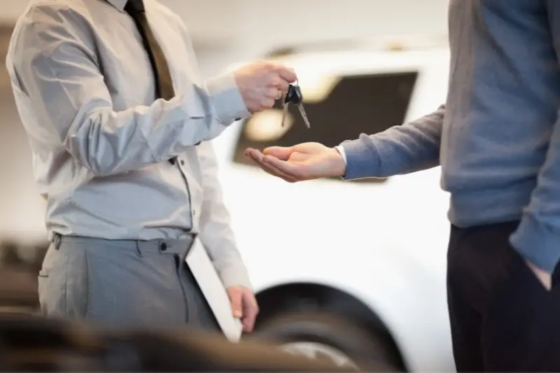 Car agent handing over the key to his client