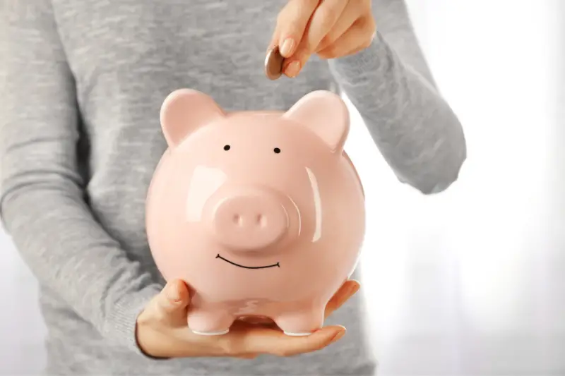 Woman putting euro coin into a piggy bank. Financial savings concept