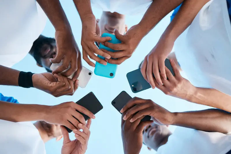 Hands, phone and app with people in a huddle or circle for communication or connectivity.
