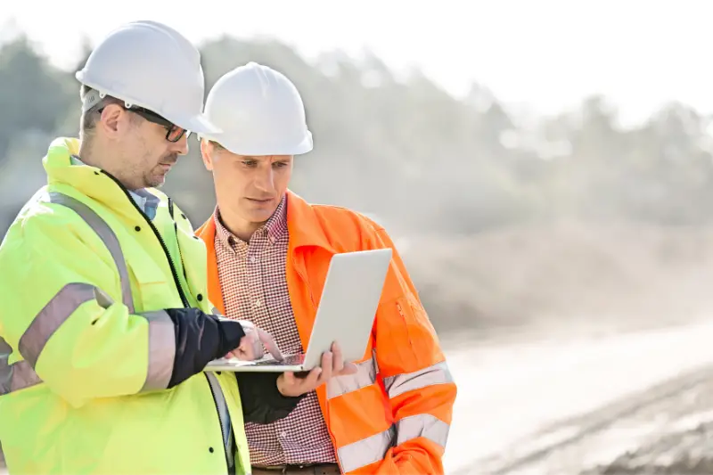 Supervisors using laptop at construction site