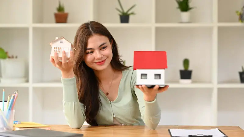 Happy young woman holding house models