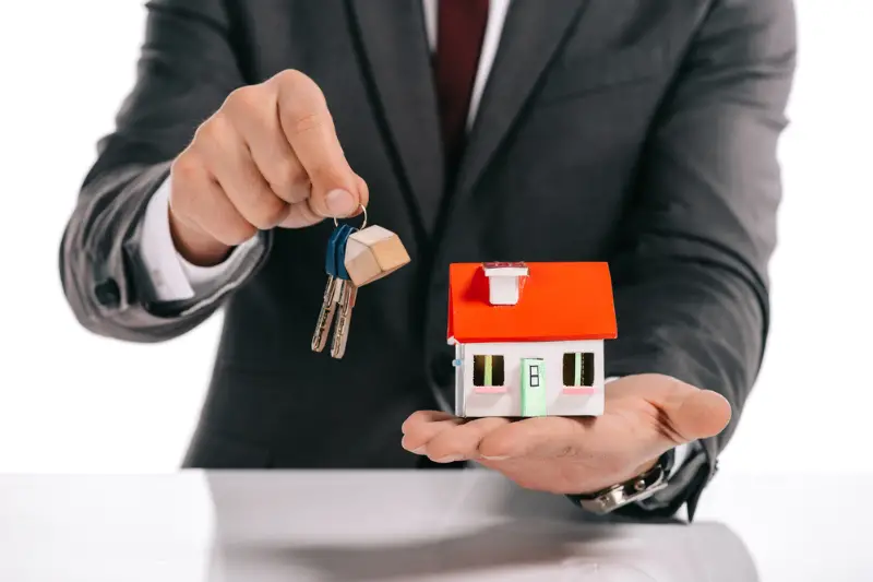 Cropped view of mortgage broker holding house model