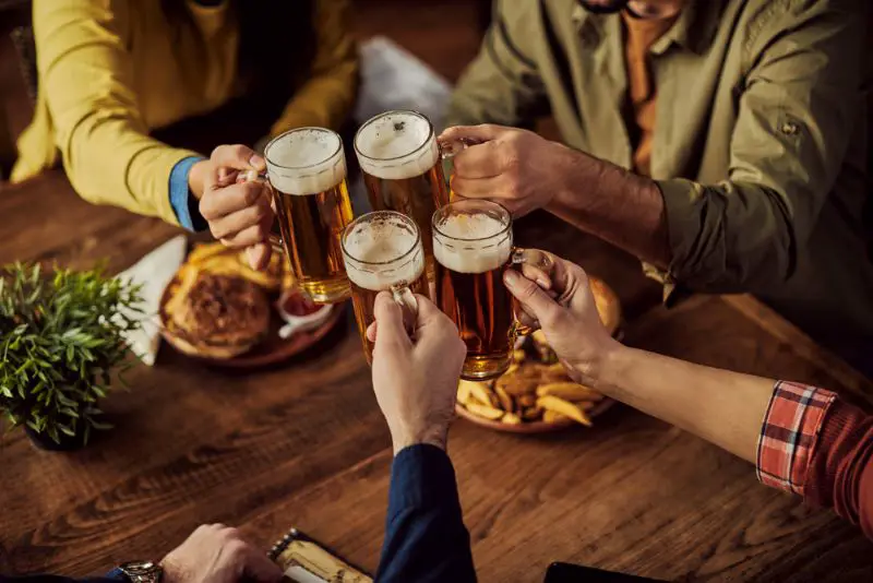 Close-up of group of people toasting with beer while eating in a pub