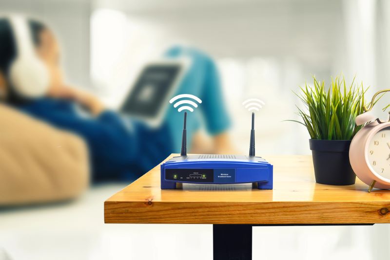 Closeup of a wireless router and a man using smartphone on living room