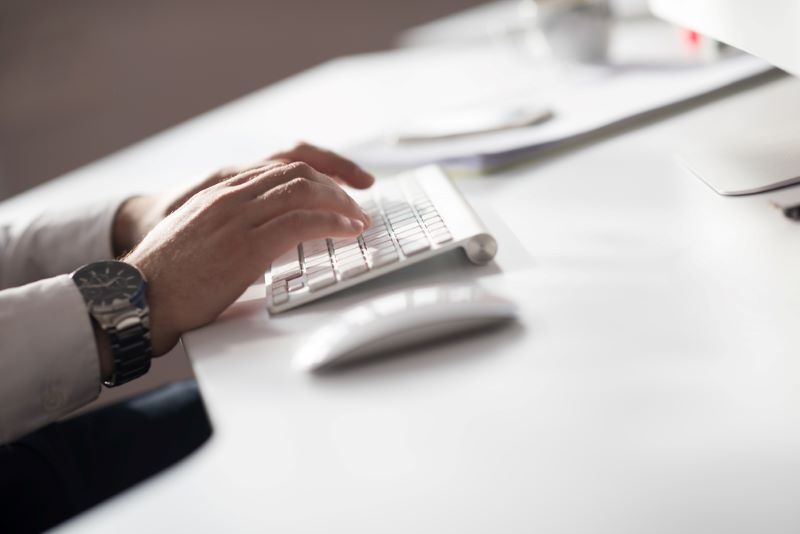 Hands typing on desktop computer