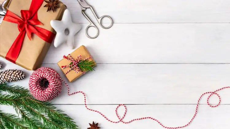 Preparing for the holidays, wrapping gifts, top view with copy space. Background with gift boxes in craft paper, striped rope, festive cookies and a branch of a Christmas tree on a table