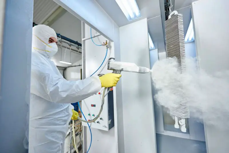 Industrial metal coating. Man in protective suit, wearing a face mask