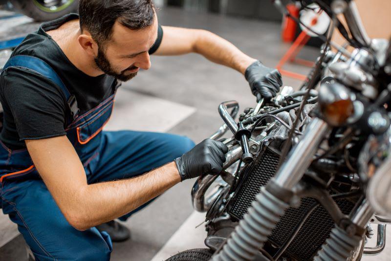 Worker repairing motorcycle engine at the workshop