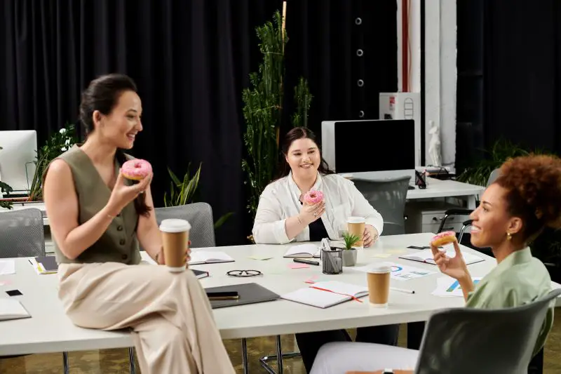 Elegant businesswomen enjoy a casual meeting in a modern office space with coffee and donuts