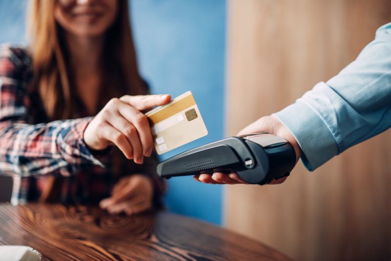 Young woman paying with credit card in cafe