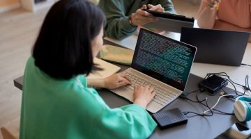 Young female student typing on laptop keyboard while decoding data