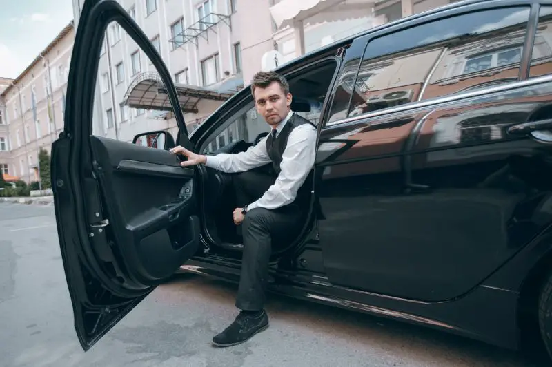 A man sitting in the driver's seat of a limousine.