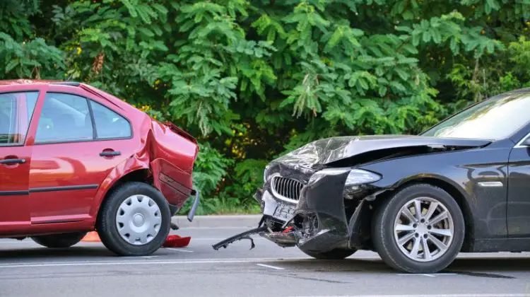 Damaged in heavy car accident vehicles after collision on city street crash site.